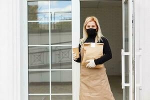 Woman in apron packaging products in paper bags for sale in workshop. Small business concept. photo