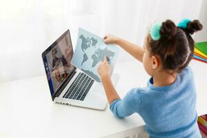 education, technology and internet concept. little girl studying geography on a laptop online photo