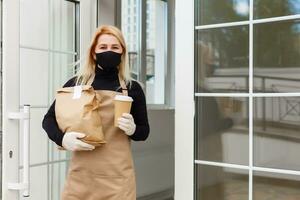 Business Owner Concept - Beautiful Caucasian Barista in face mask offers hot coffee at the modern coffee shop photo