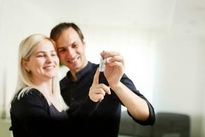 Happy smiling young couple showing a pair of keys of their new house photo