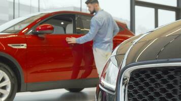 joven hermoso hombre examinando carros vendido a automóvil concesión video