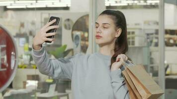 encantador joven mujer tomando selfies con su inteligente teléfono a el compras centro comercial video