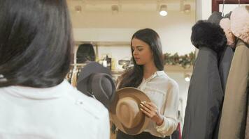 Attractive woman trying on hats in front of the mirror video