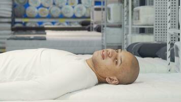 Happy African man lying on orthopedic mattress at furniture store video