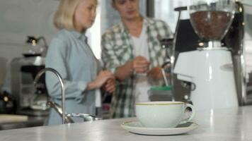 selektiv fokus på en kaffe kopp två baristas arbetssätt på bakgrund video