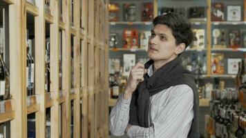 joven hermoso hombre sonriente a el cámara mientras compras a vino Tienda video