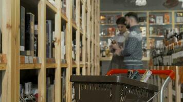 Wine bottles in shopping cart shop assistant and customer talking on background video