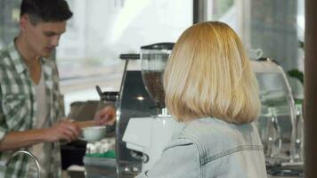 joven mujer sonriente a el cámara después consiguiendo un taza de café a el café tienda video