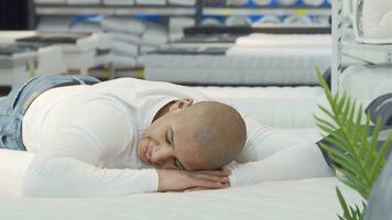 Young man trying orthopedic mattress at furniture store video