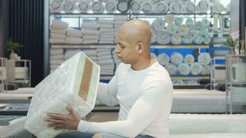 Handsome man examining sample of orthopedic mattress on sale video