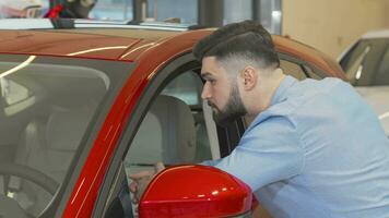 Male customer smiling to the camera while examining new car on sale video