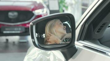 mooi gelukkig vrouw glimlachen naar de camera door kant spiegel van haar auto video