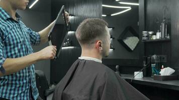 Barber holding a mirror for his male client to check out new haircut video