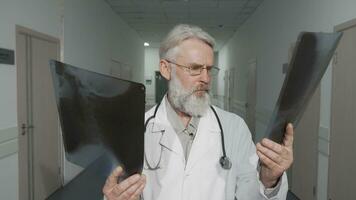 Cheerful senior male doctor smiling to the camera while comparing two xray scans video