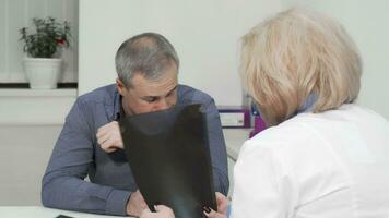 Mature man coughing at medical appointment with his doctor video