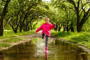 happy child girl with rubber boots in puddle on an autumn walk photo