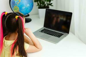 Cool online school. Kid studying online at home using a laptop. Cheerful young little girl using laptop computer studying through online e-learning system. Distance or remote learning photo