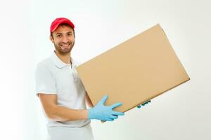 Smiling young delivery man holding and carrying a cardbox isolated on white background photo