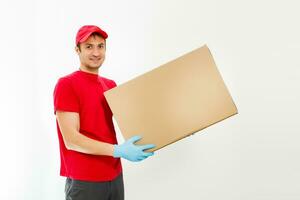 Smiling young delivery man holding and carrying a cardbox isolated on white background photo