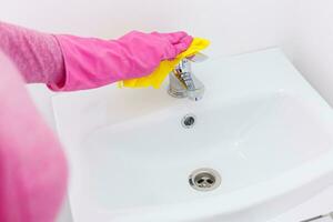 Hand with sponge cleaning white sink. photo