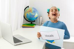 Little girl at speech therapist office, little girl learns vocal on laptop online, distance learning photo