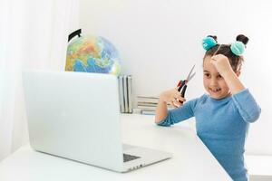 little girl learning hair cutting on laptop online photo