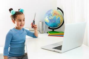 little girl learning hair cutting on laptop online photo