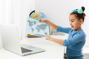 education, technology and internet concept. little girl studying geography on a laptop online photo