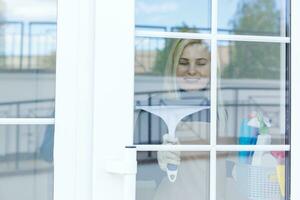 mujer limpieza un ventana con un herramienta foto