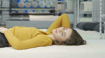 feliz jovem mulher desfrutando deitado em Novo colchão às mobília loja video