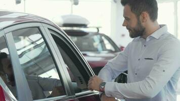 bello uomo sorridente per il telecamera mentre l'esame auto per vendita a concessionaria video