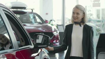 Lovely woman examining cars for sale at dealership video