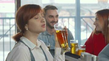 charmant femme souriant à le caméra tandis que en buvant délicieux Bière video