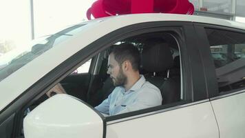 bello allegro uomo mostrando auto chiavi per il telecamera seduta nel il suo nuovo auto video