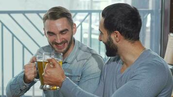 Happy male friends clinking beer glasses enjoying drinking at the pub video