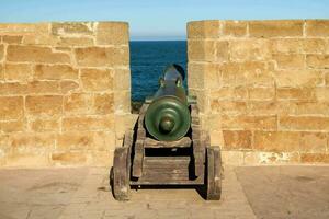 a cannon is sitting in a stone wall near the ocean photo