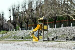 a playground with a slide and benches near the water photo