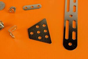 a group of metal clips and screws on a orange surface photo