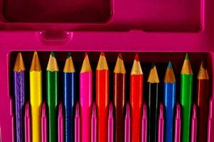 a pink pencil case with several colored pencils photo