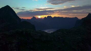 volante al di sopra di il montagne e fiordo. bellissimo tramonto e drammatico cielo nel il montagne. lofoten isole. Norvegia. 4k video