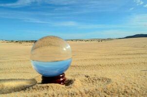 a glass ball sitting in the sand photo