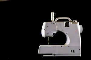 un de coser máquina es mostrado en un negro antecedentes foto