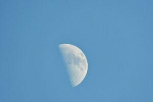 the moon is seen in a clear blue sky photo
