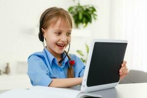 inteligente pequeño Chica de escuela con digital tableta en un aula. niño en un elemental escuela. educación y aprendizaje para niños. foto