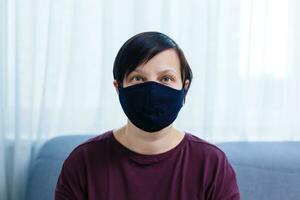 Close up woman portrait, Young woman wearing home made hygienic face medical mask to prevent infection, illness or flu and 2019-nCoV. Black background. Protection against disease, coronavirus. photo