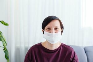 Close up woman portrait, Young woman wearing home made hygienic face medical mask to prevent infection, illness or flu and 2019-nCoV. Black background. Protection against disease, coronavirus. photo