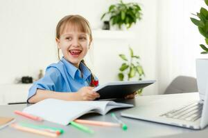 inteligente pequeño Chica de escuela con digital tableta en un aula. niño en un elemental escuela. educación y aprendizaje para niños. foto