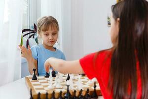 dos pequeño hermana jugando ajedrez a hogar foto