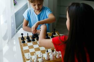 dos pequeño hermana jugando ajedrez a hogar foto