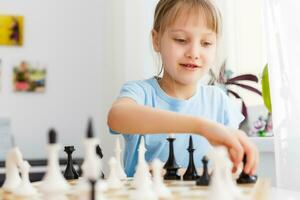 niña Moviente un mostrador mientras jugando ajedrez foto